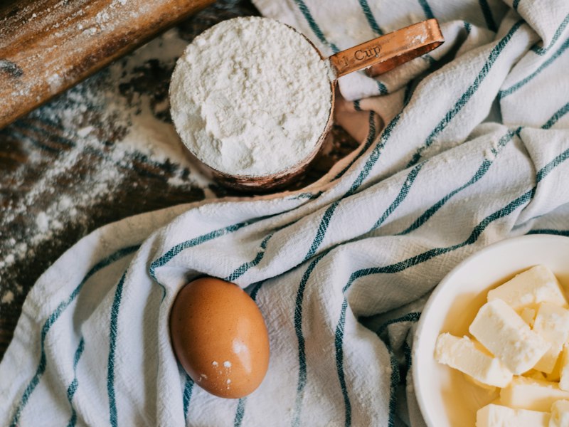 Flour, an egg and butter on a striped kitchen towel